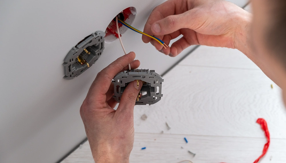 Professional electrician working on a home electrical system, he is installing a wall socket